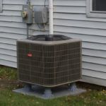 An air conditioner is sitting on the side of a house.