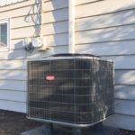 A large air conditioner is sitting on the side of a house.