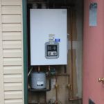 A white boiler is sitting inside of a building next to a door.