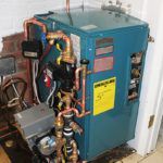 A blue water heater is sitting in a room next to a wall.