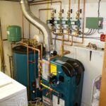 A blue boiler is sitting in a room next to a washer and dryer.