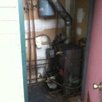 A boiler is sitting in a room next to a door.