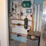 A room with a boiler and pipes on the wall.