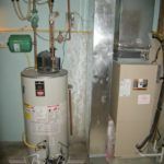 A water heater is sitting next to an air conditioner in a room.