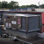 A large air conditioner is sitting on top of a roof.