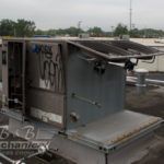 A large air conditioner is sitting on top of a roof.