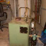 A green machine is sitting in a room next to a chair.