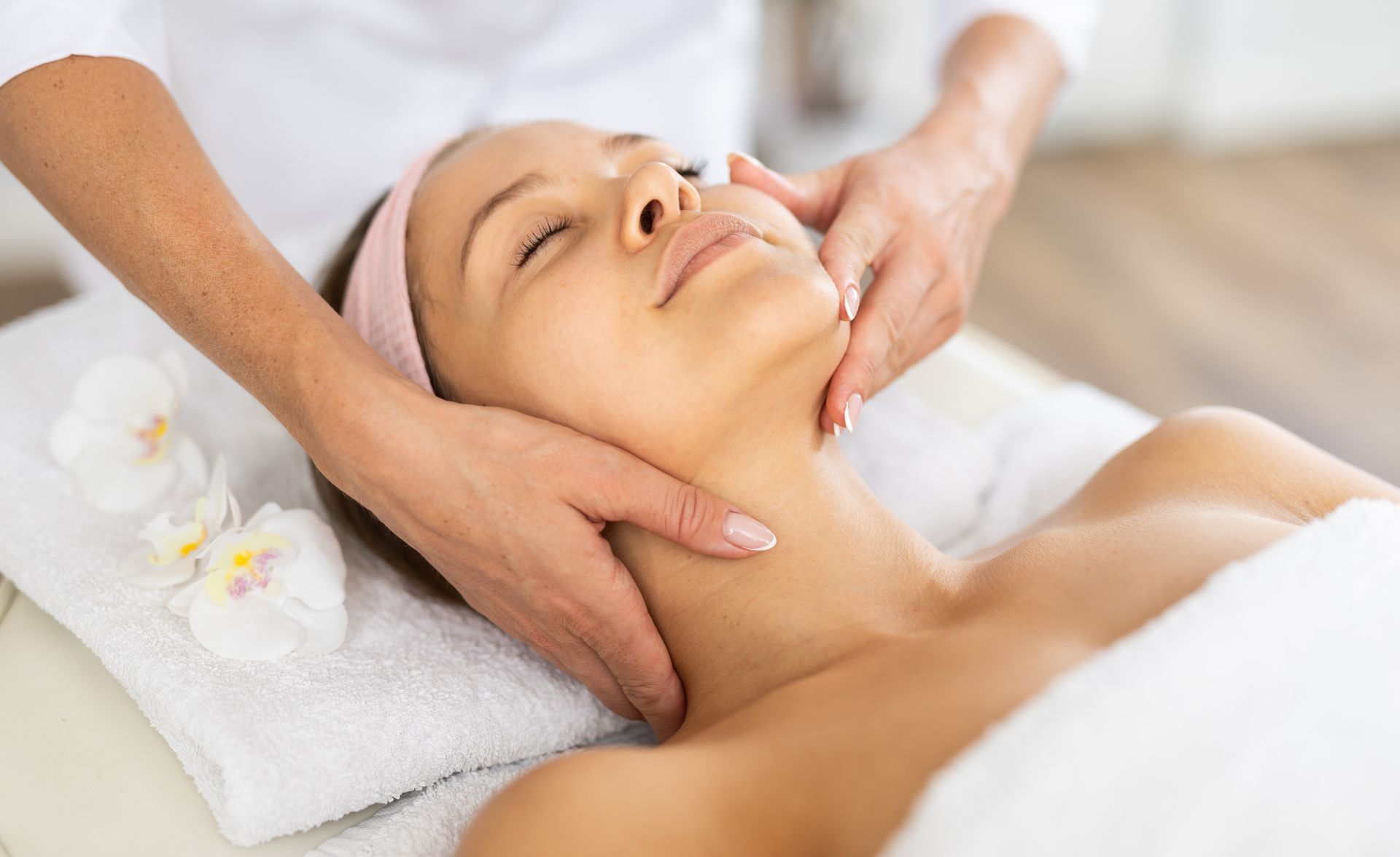 A woman is getting a facial massage at a spa.