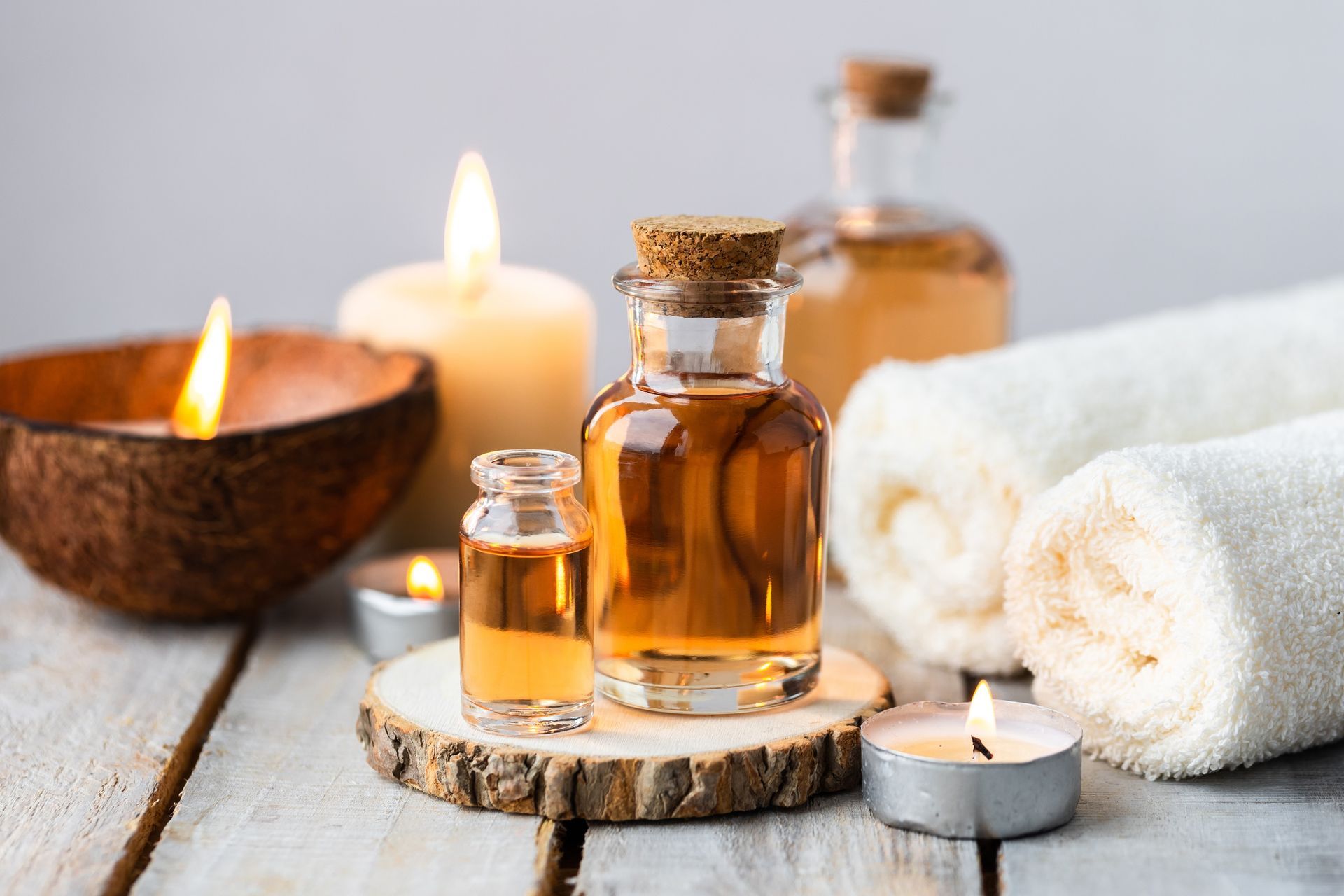 A wooden table topped with bottles of essential oil , candles and towels.
