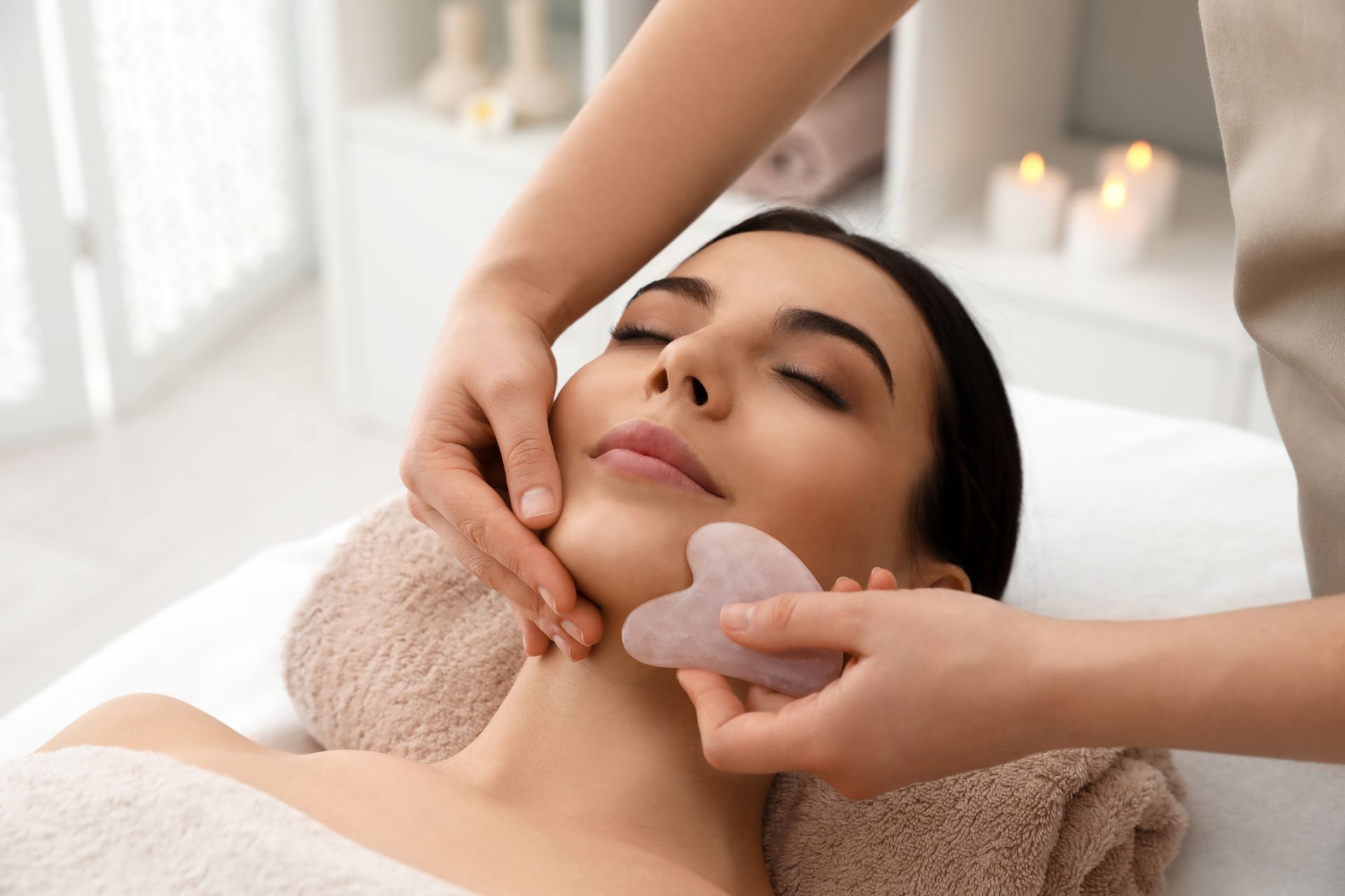 A woman is getting a facial massage at a spa.