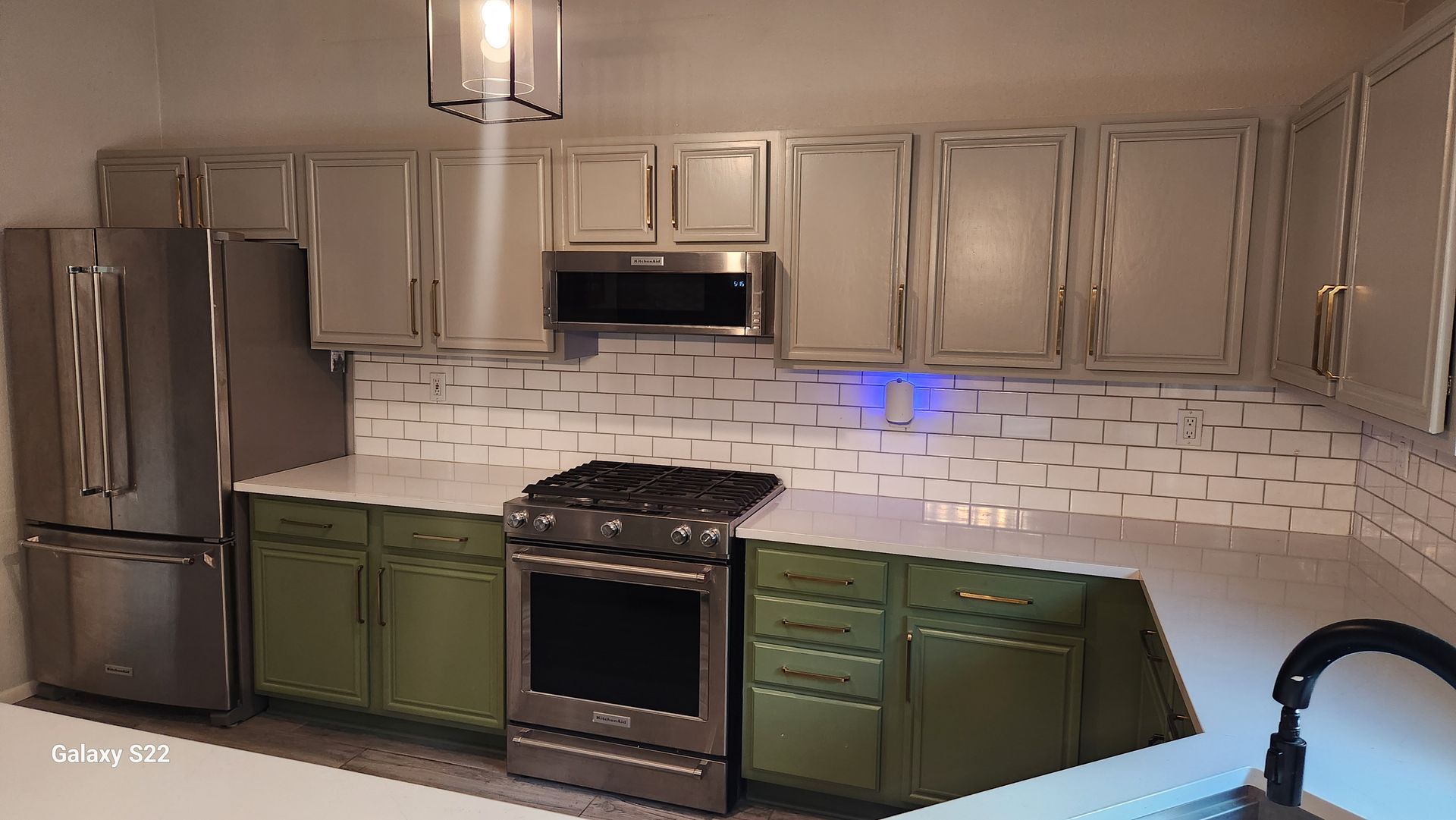 Kitchen with stainless steel appliances, green cabinets, and white countertops.