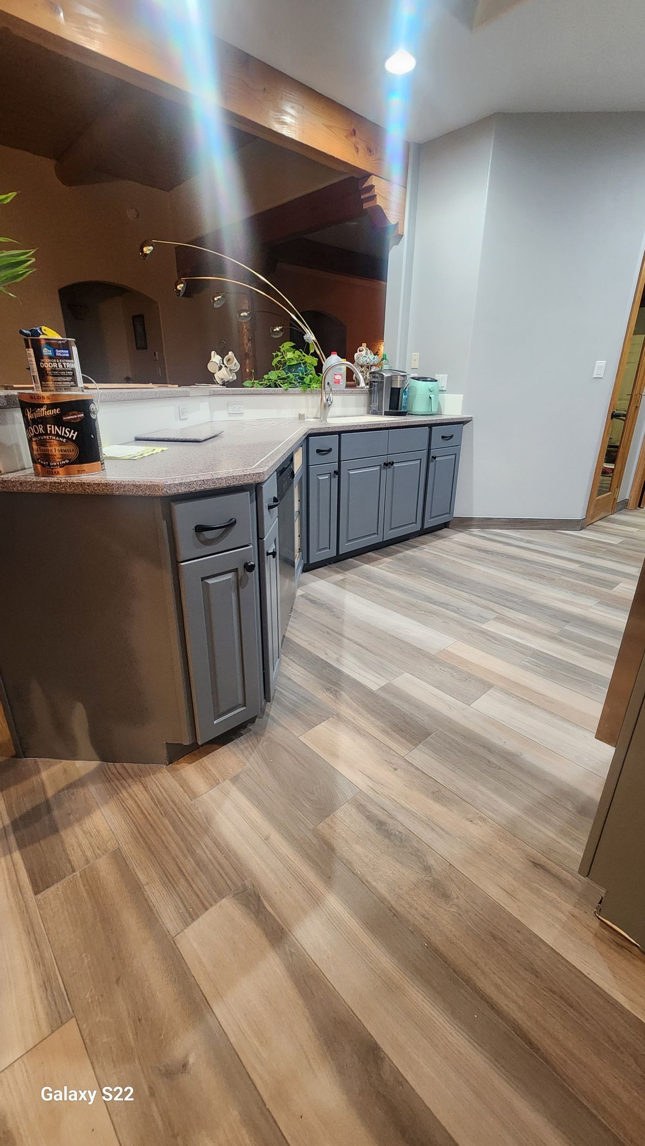 Kitchen counter with grey cabinets, granite top, and wood-look flooring.