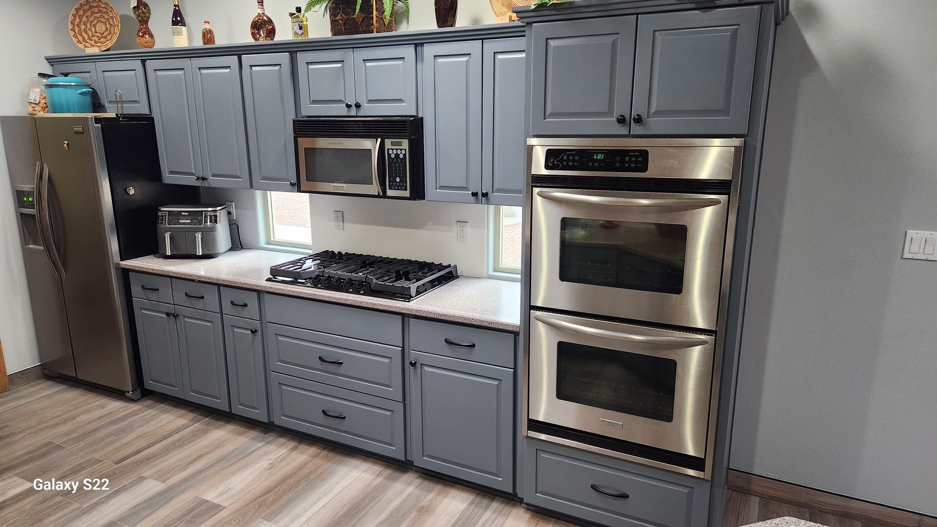 Kitchen with grey cabinets, stainless steel appliances, and white countertops.