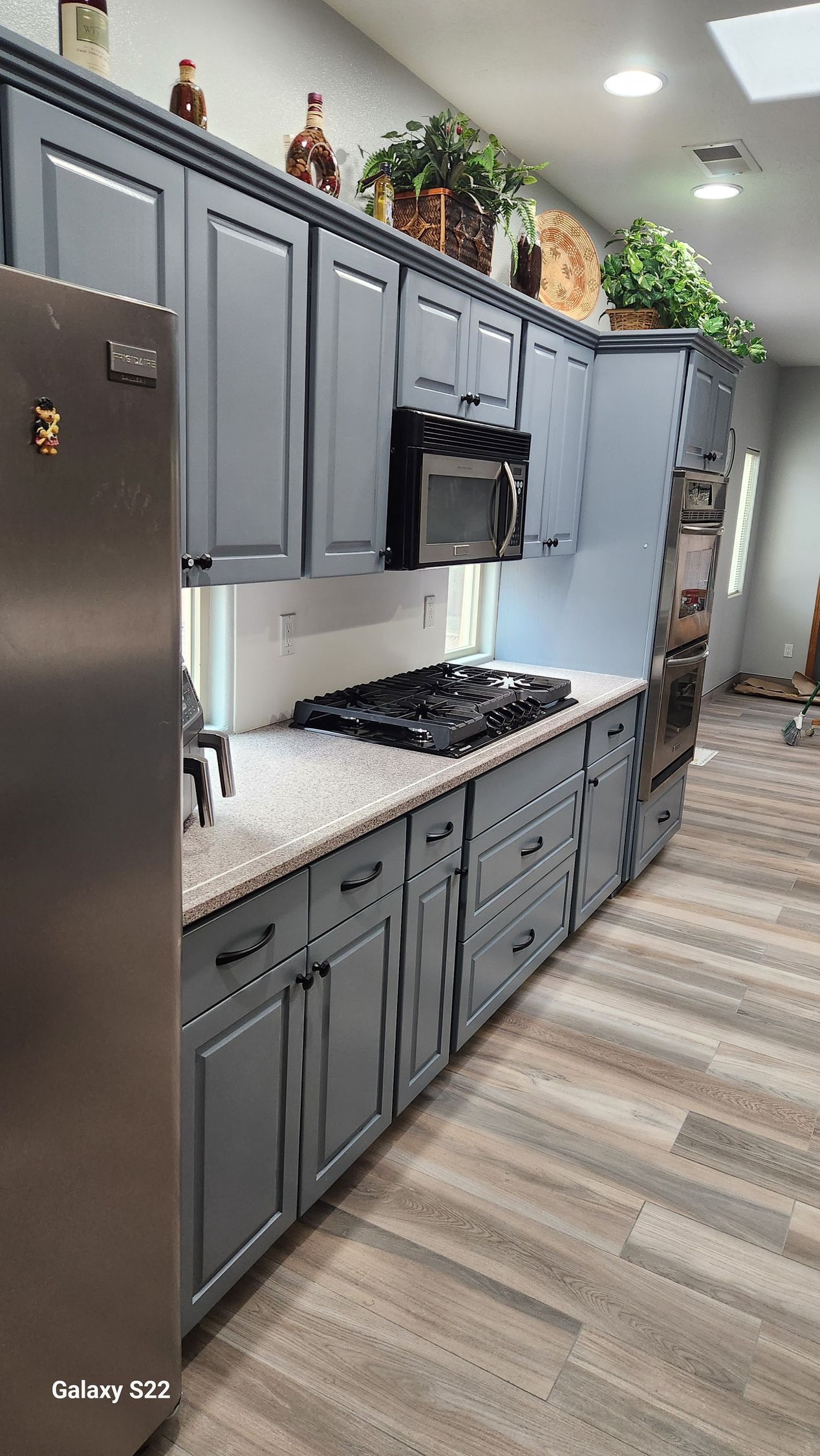 Gray kitchen cabinets, countertops, and appliances with overhead lighting.