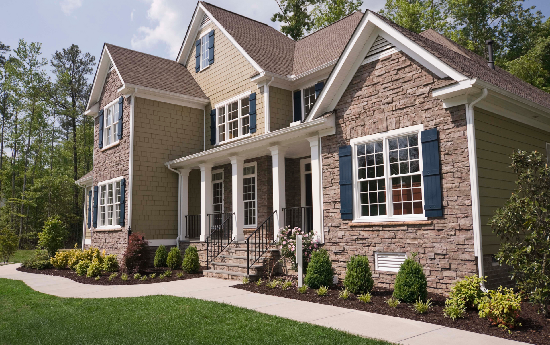 Two-story house with stone facade and brown siding, blue shutters, and white trim.