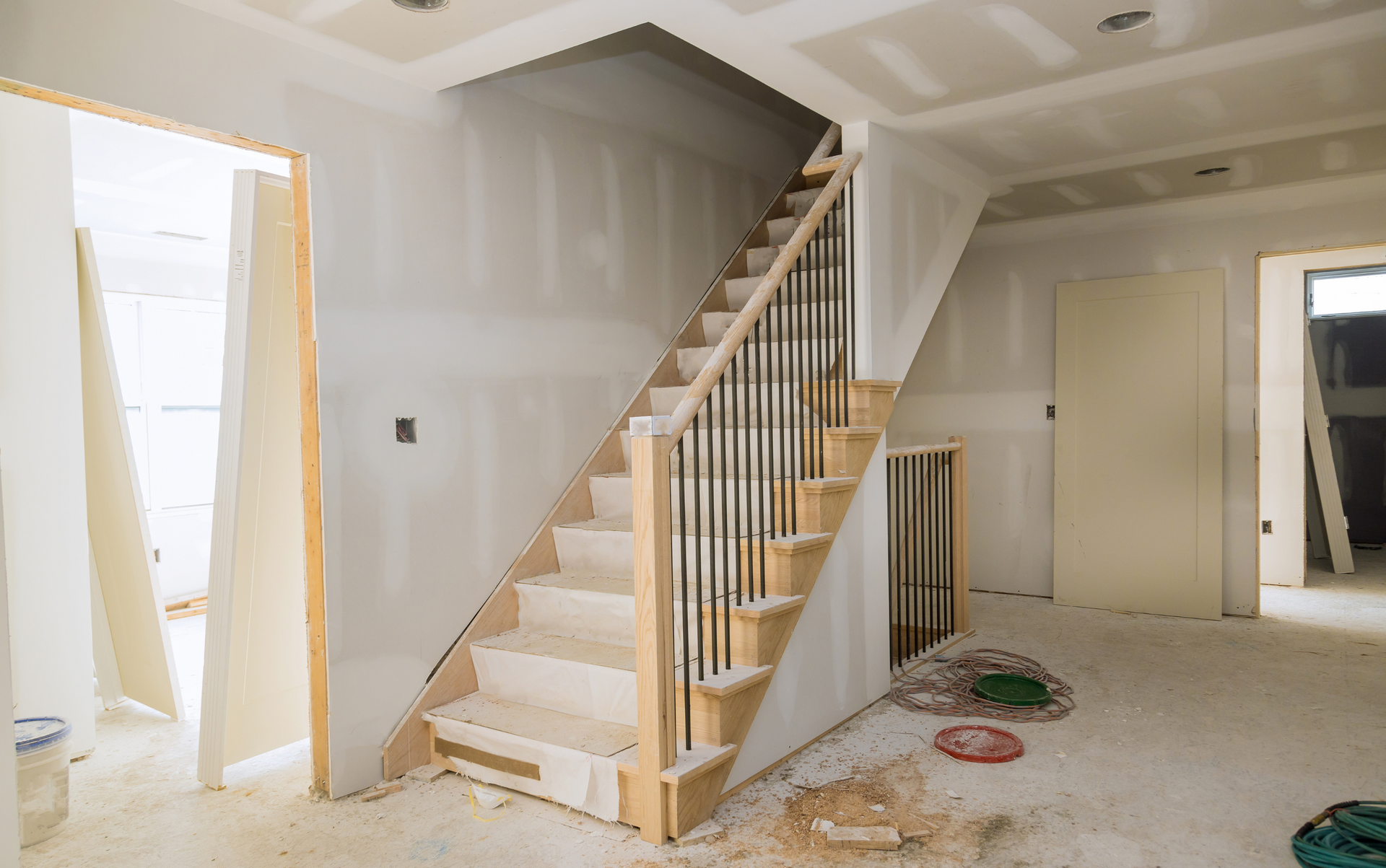 Interior view of a staircase under construction with drywall and unfinished walls.
