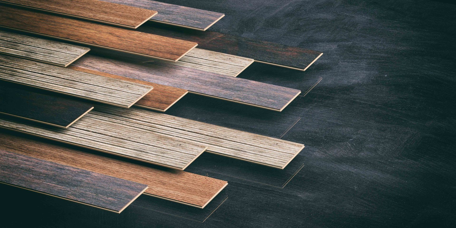 Wooden planks arranged diagonally, with varying colors and textures, on a dark textured surface.