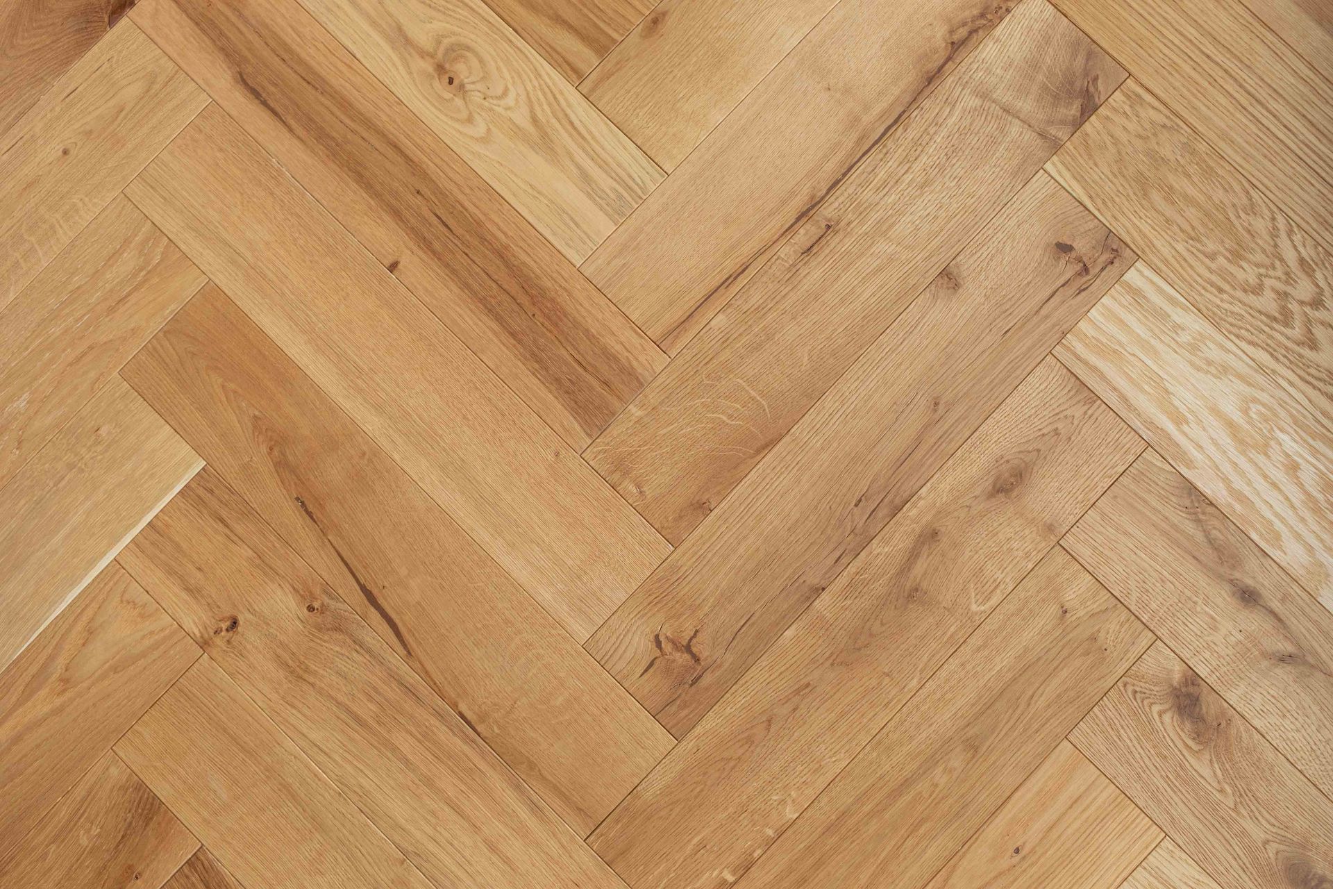 Herringbone pattern wooden floor in shades of light brown.