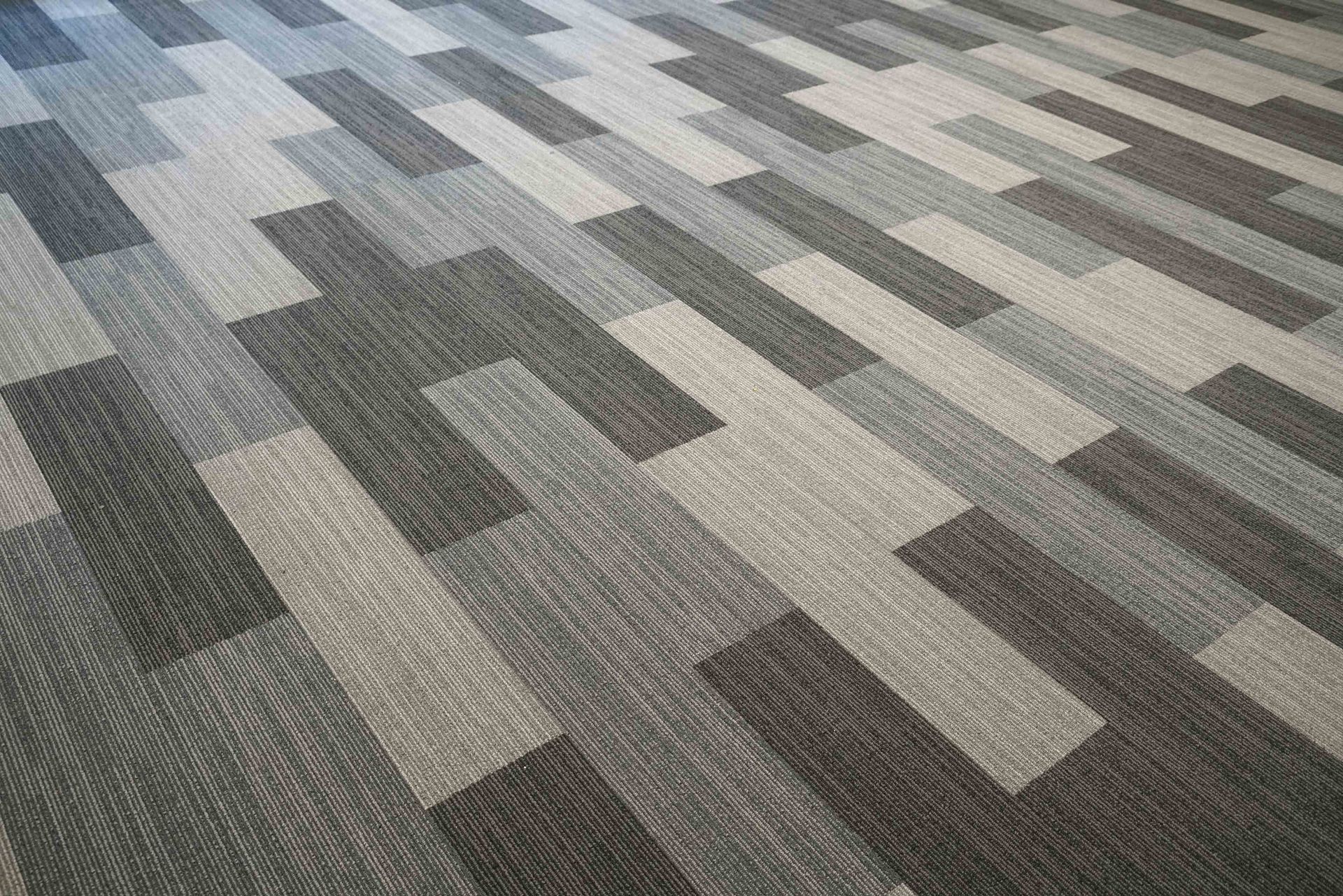 Gray and beige rectangular floor tiles arranged in a staggered pattern.
