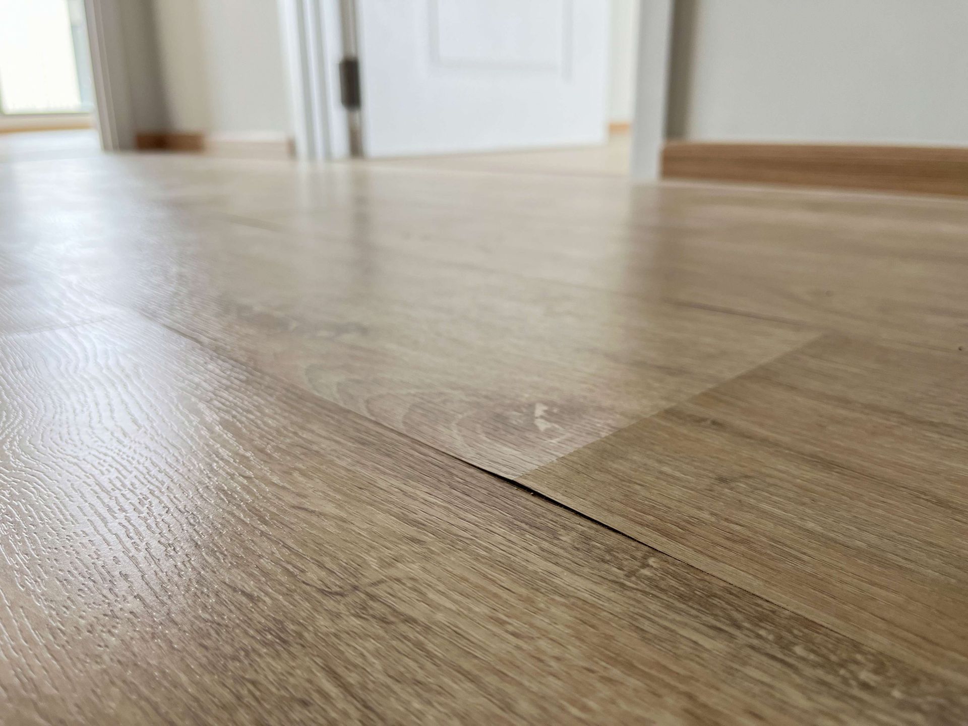 Close-up of light brown wood flooring with a visible gap between two planks, indoors.