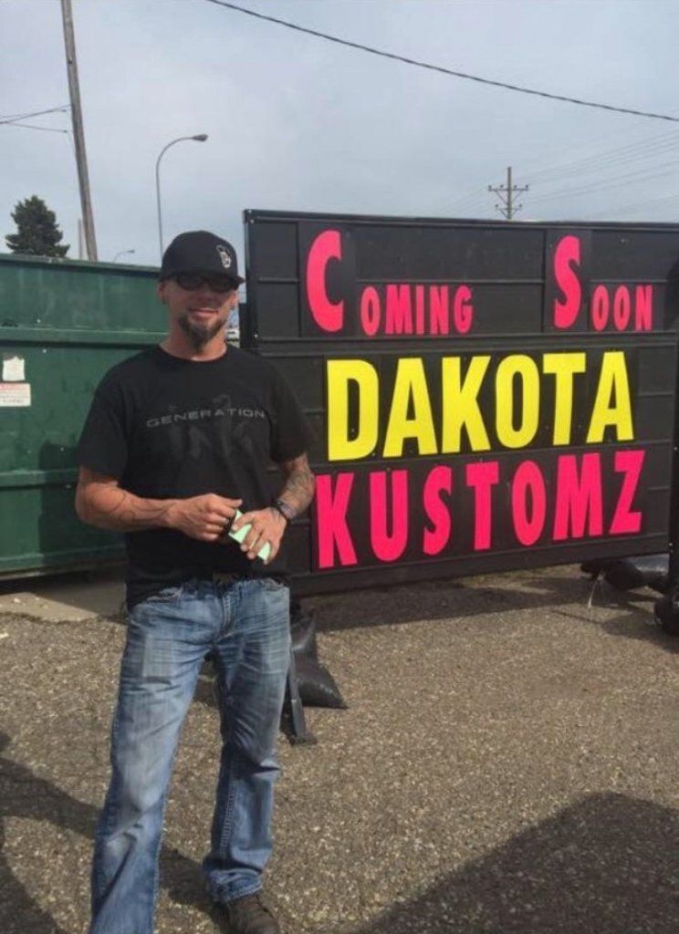 owner travis feist in front of dakota kustomz coming soon sign