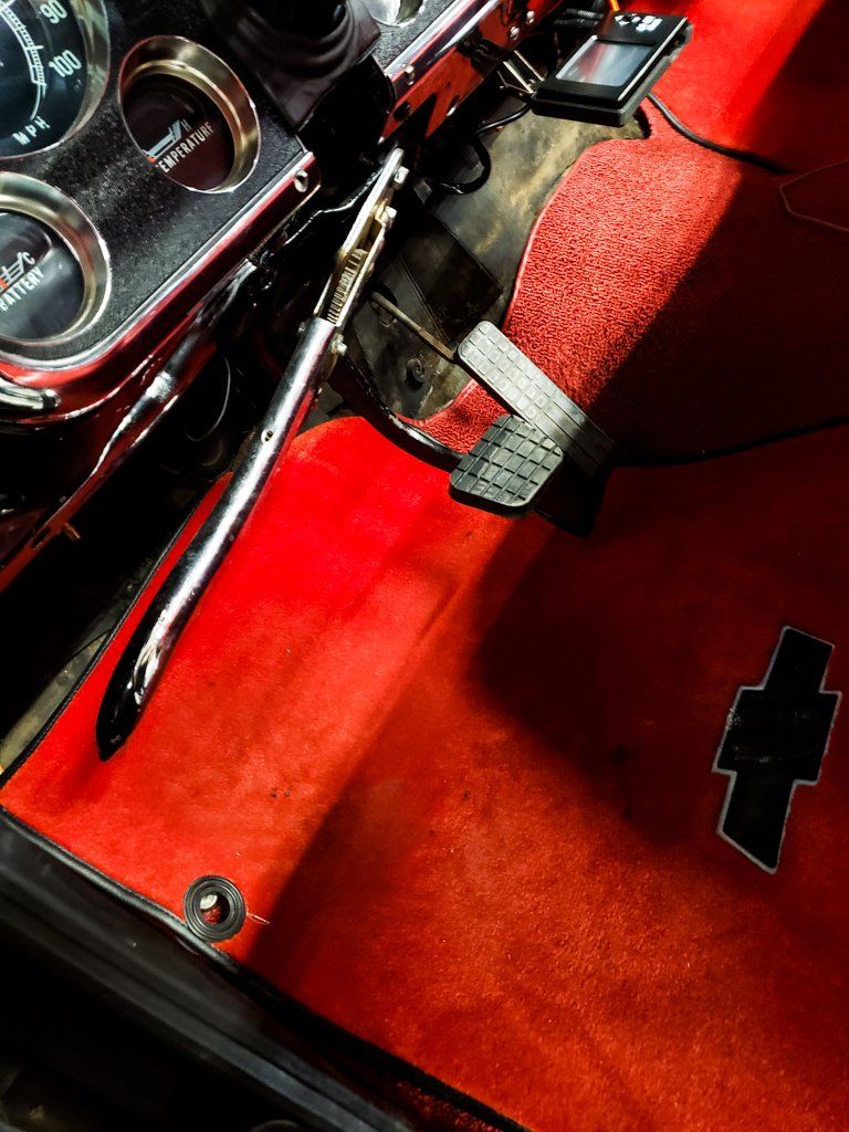close up of customized driving pedals in red interior of black 1968 RJ C10