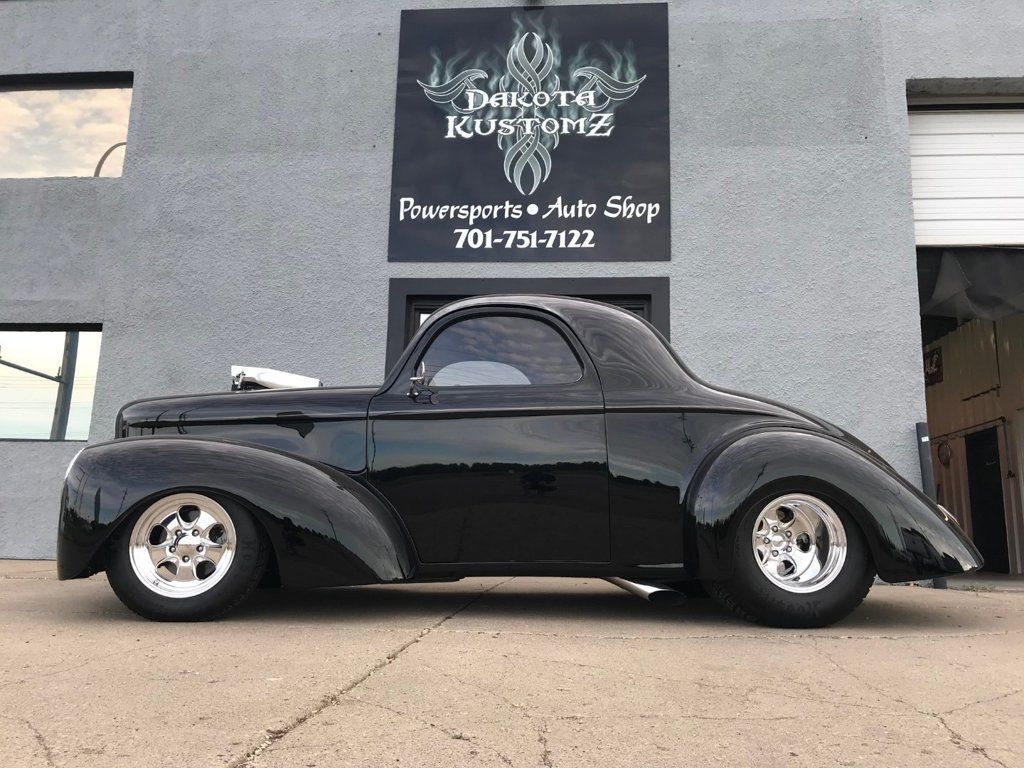 side view of custom black 1941 willys coupe with dakota kustomz building in the background
