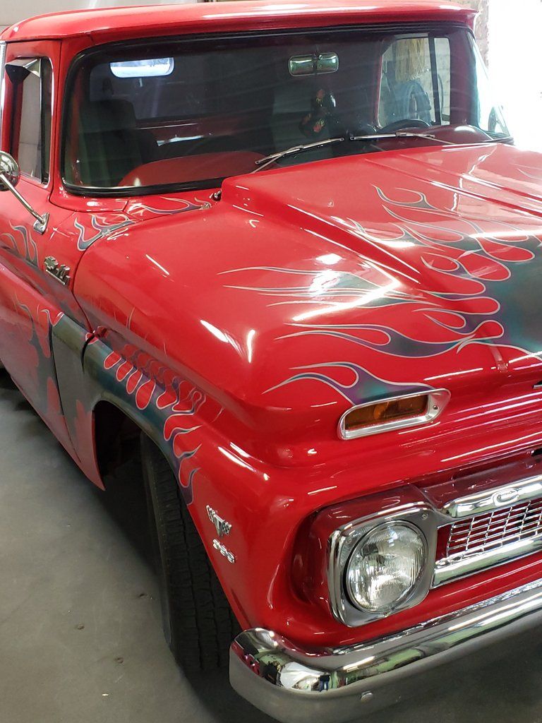 front side view of passenger side of 1962 customized red truck with grey flames