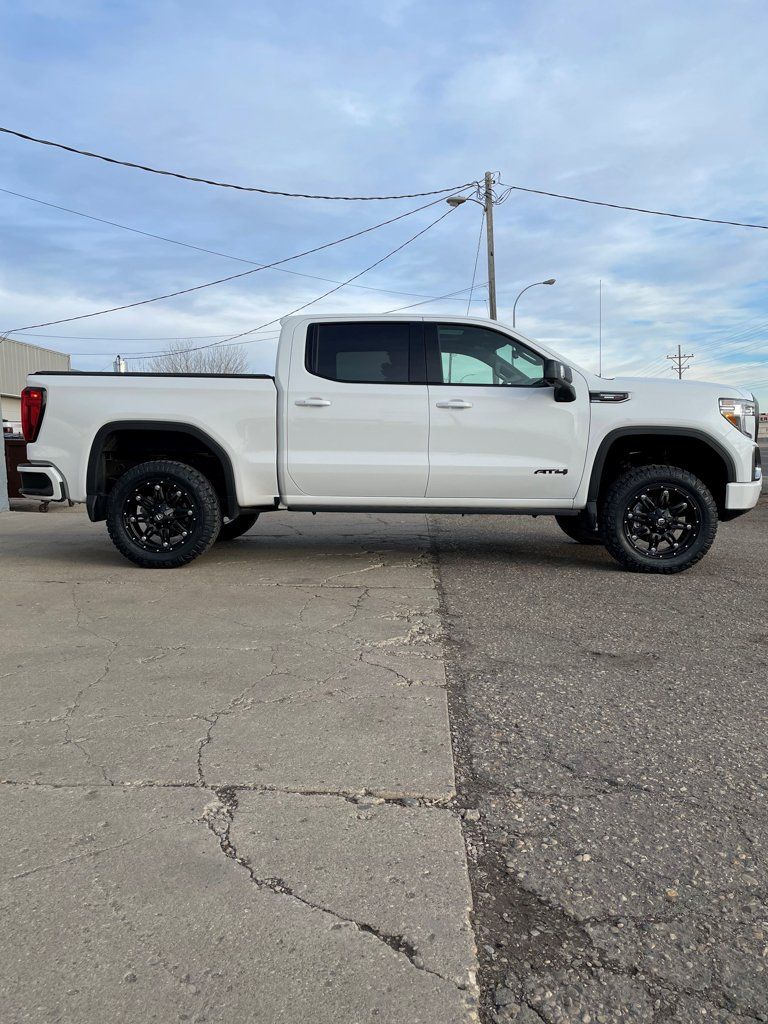 side view of customized white 2021 GMC AT4 in concrete lot