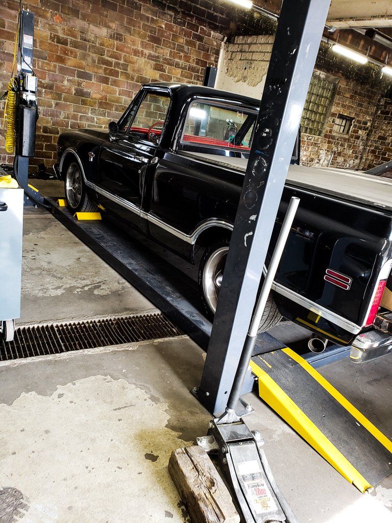 side rear view of black 1968 RJ C10 in service bay
