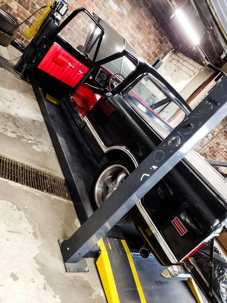 side rear view of black 1968 RJ C10 in service bay with drive door open