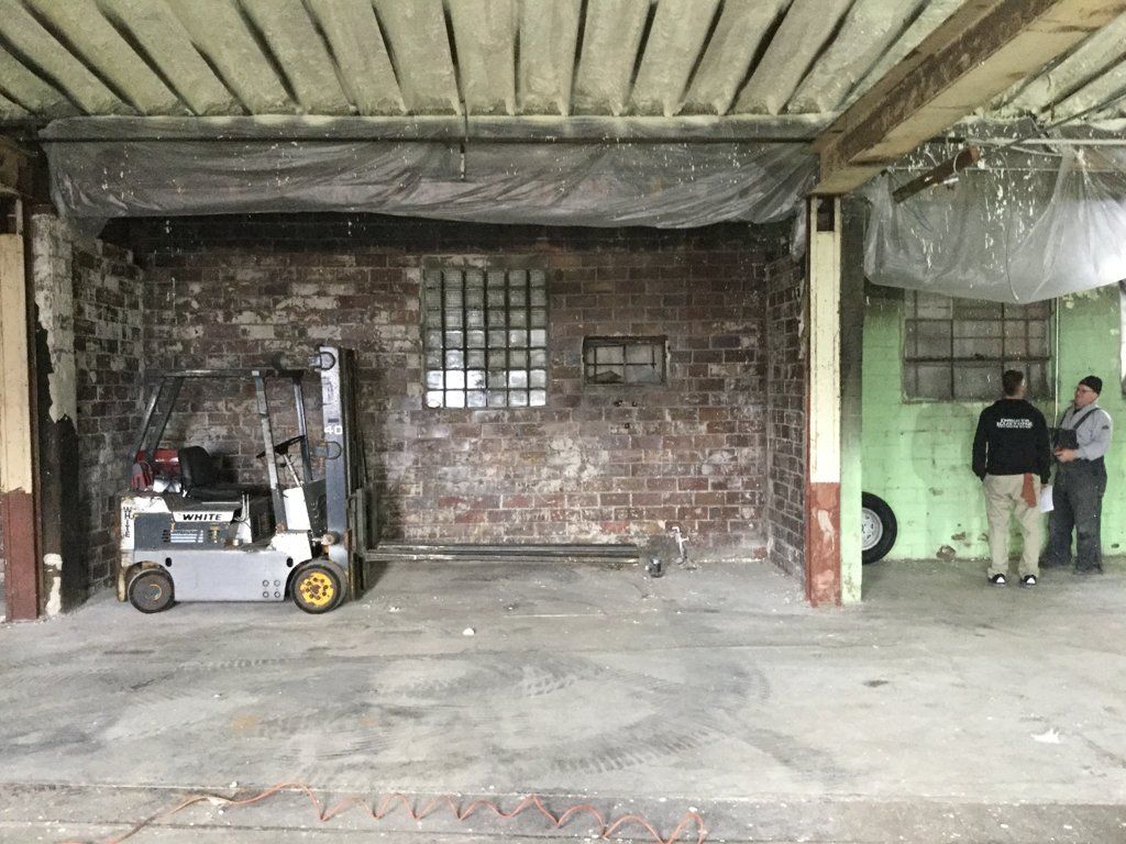 room with ceiling under construction with forklift and workers discussing in the background