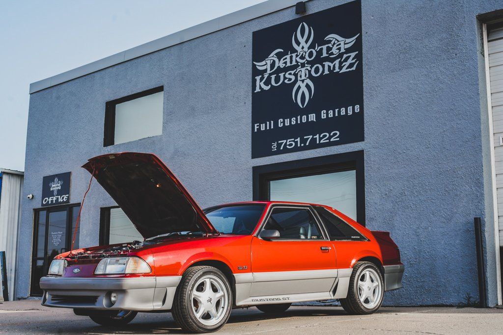 car with hood open in front of dakota kustomz garage