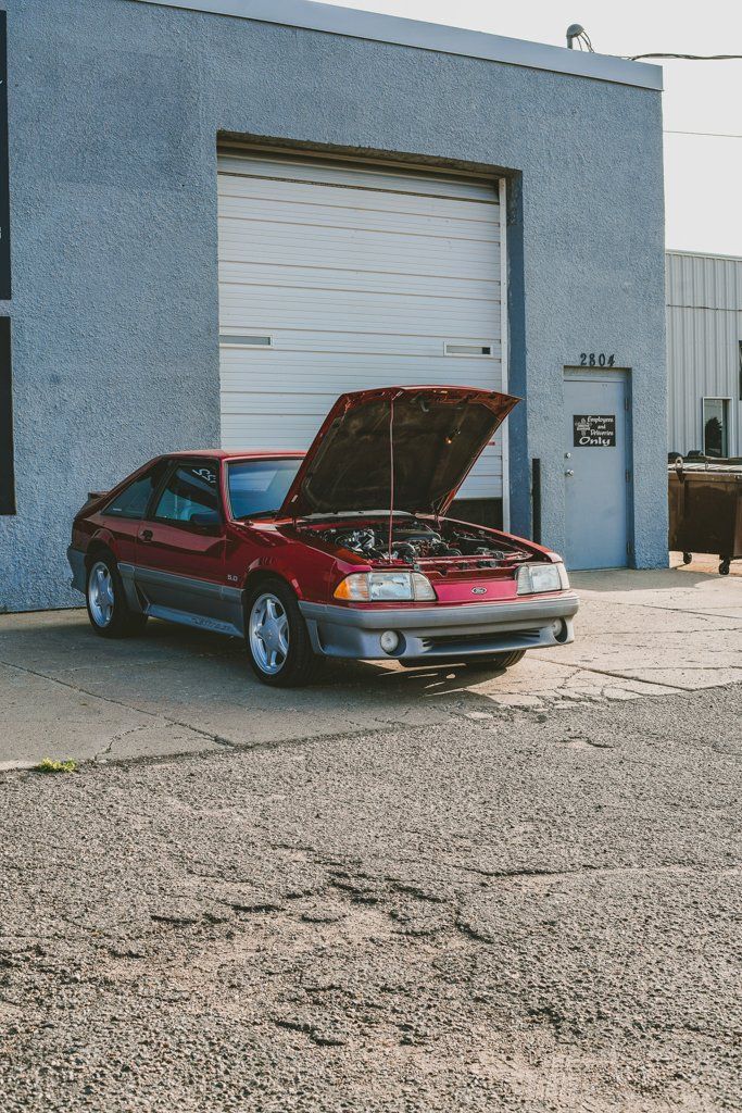 car with hood open in front of close garage