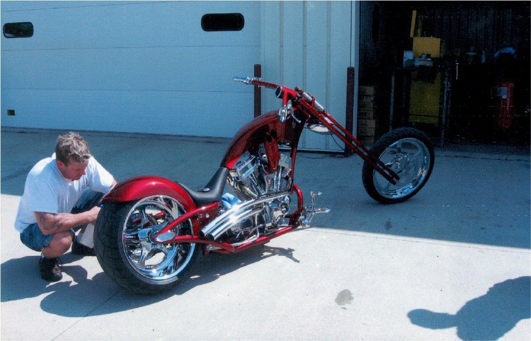 mechanic inspecting rear view of customized red chopper