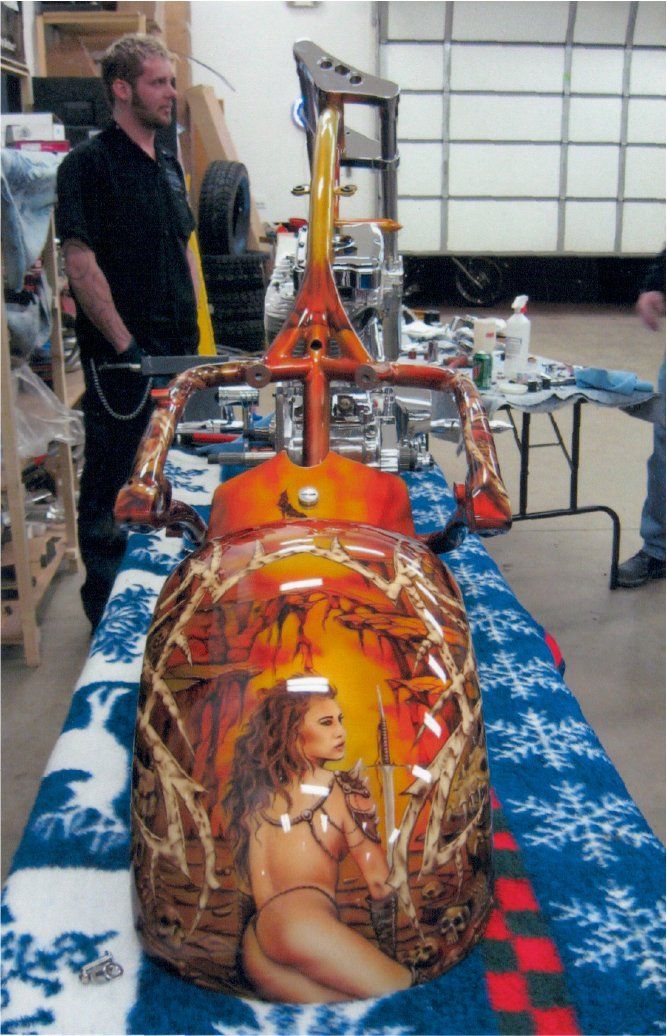rear view of custom orange and red chopper frame on workbench