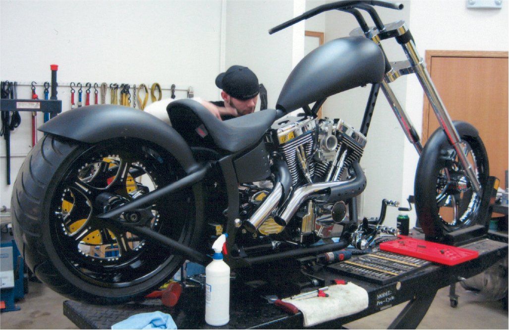 mechanic inspecting parts on customized chopper on workbench