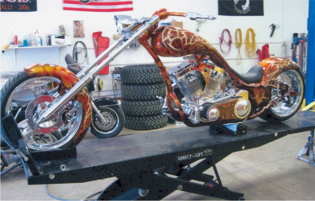 side view of custom orange and red chopper on service bay