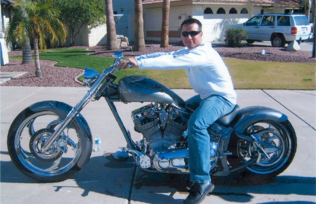 side view of fully customized gothic chopper with rider on side walk