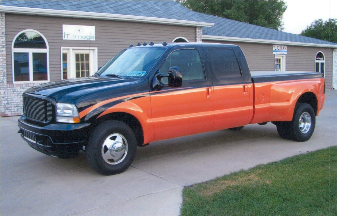 custom black and orange Dakota Kustomz shop pickup truck in front of office building