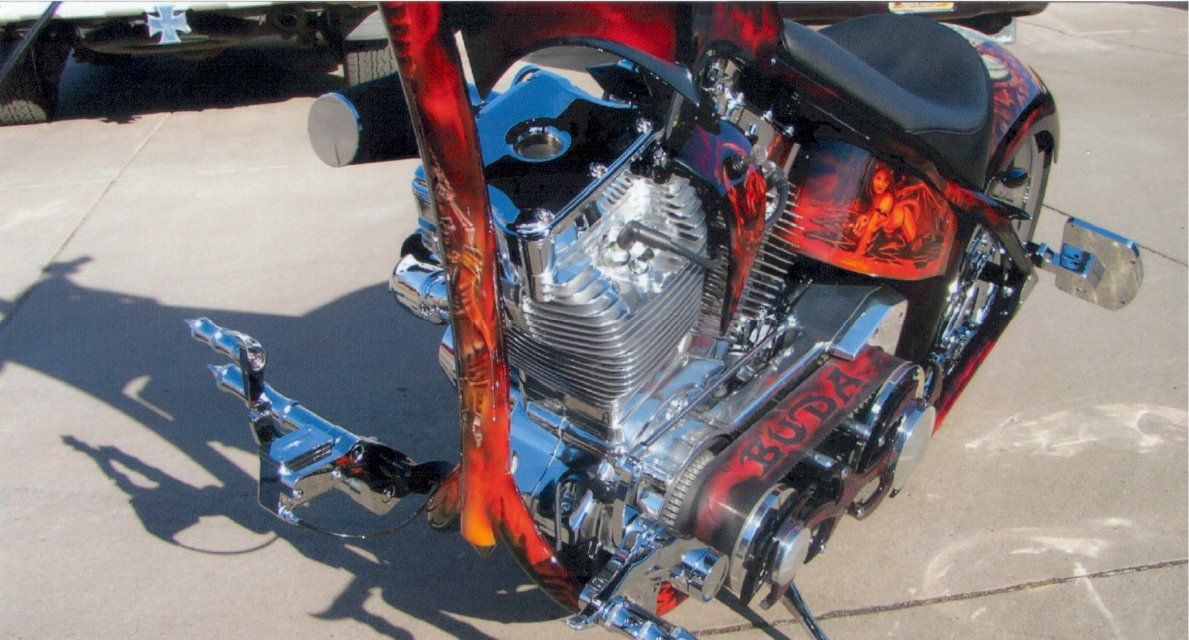 close up of engine and custom orange and red frame with engine belt with the word 