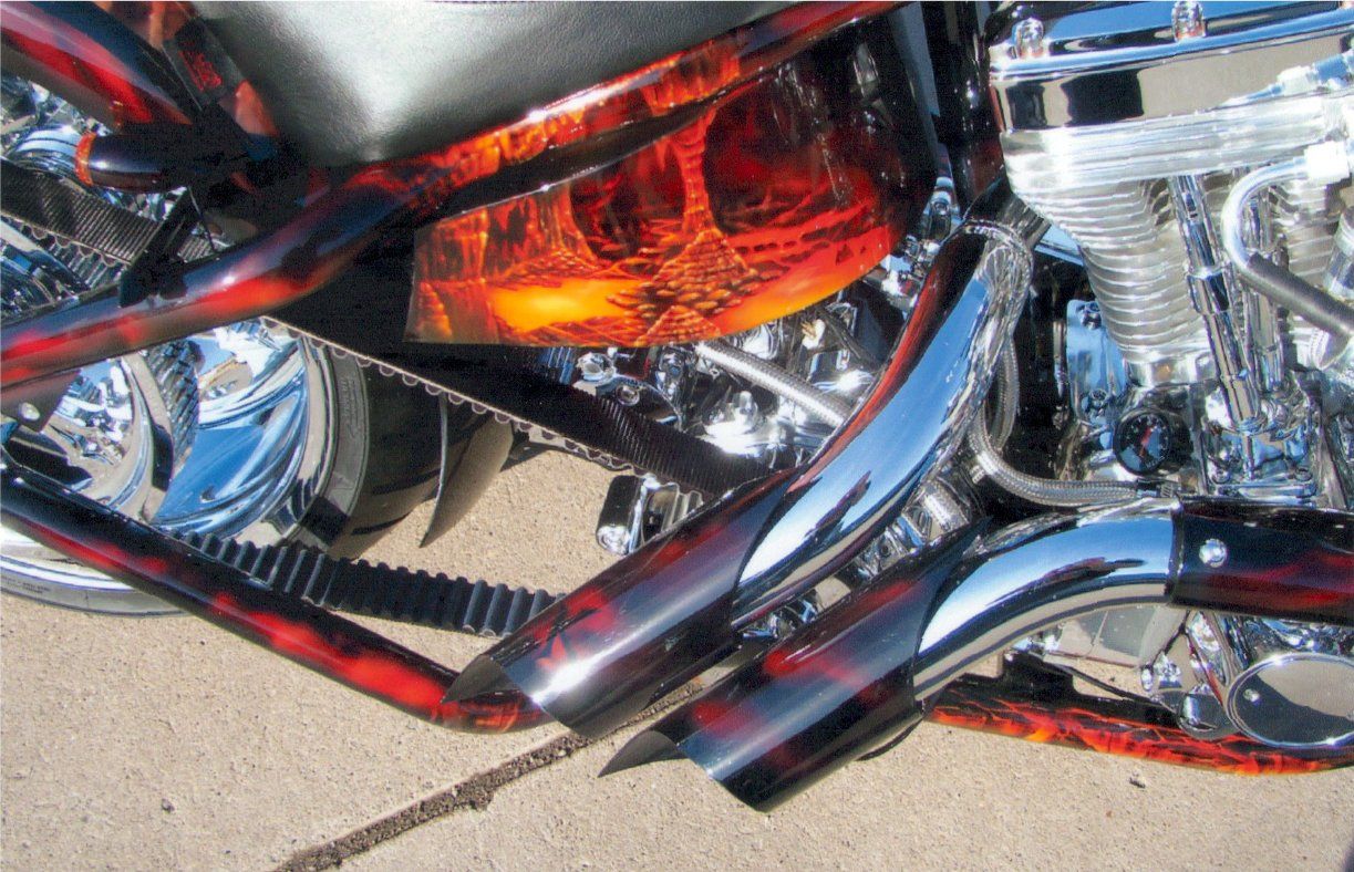 customized red, orange, and chrome exhaust pipes and artwork decals on chopper
