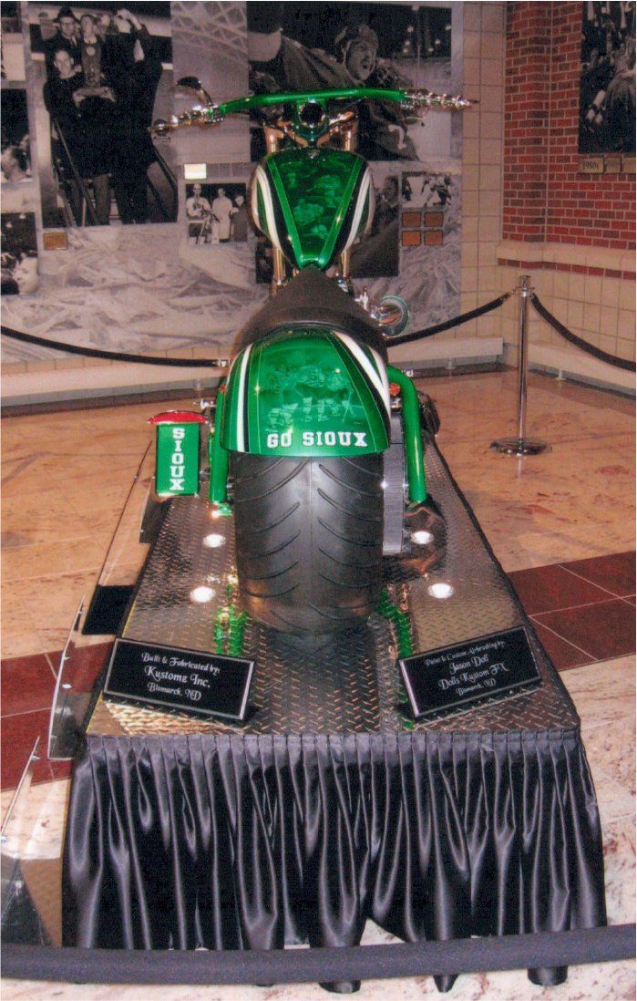 rear view of customized green chopper on display show case indoors