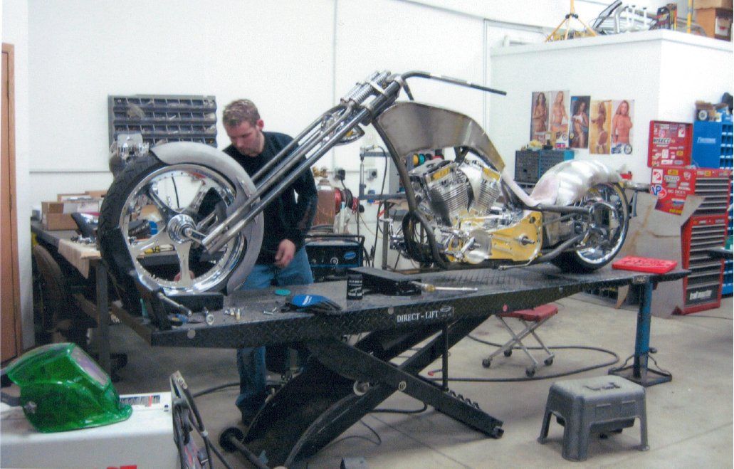 full chopper on workbench with mechanic in background