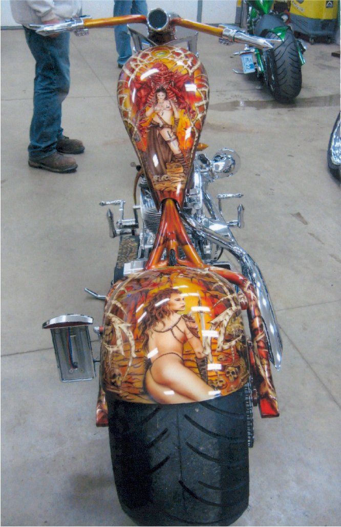 rear driver view of custom orange and red chopper featuring gothic art