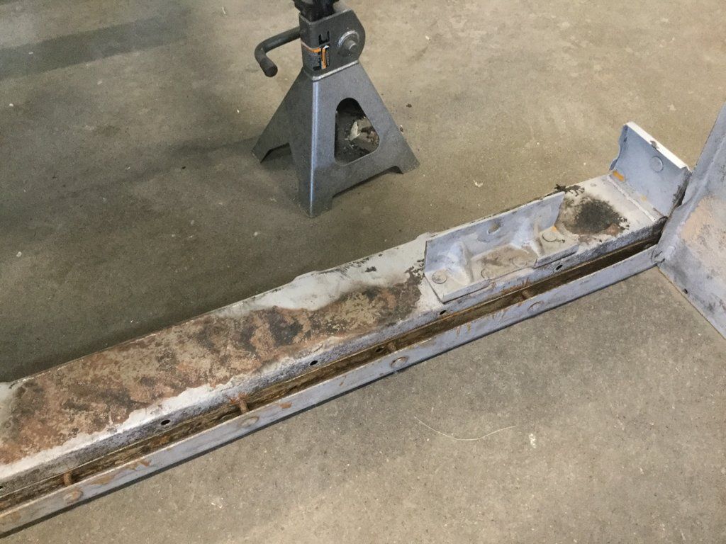 near rusted truck part on ground next to metal riser