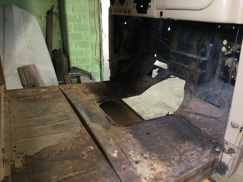 rusted truck floor with seats and pedals removed