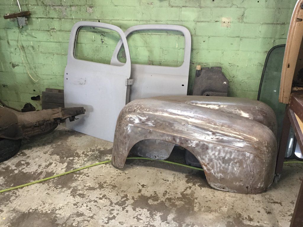 truck parts and doors leaning against wall of garage