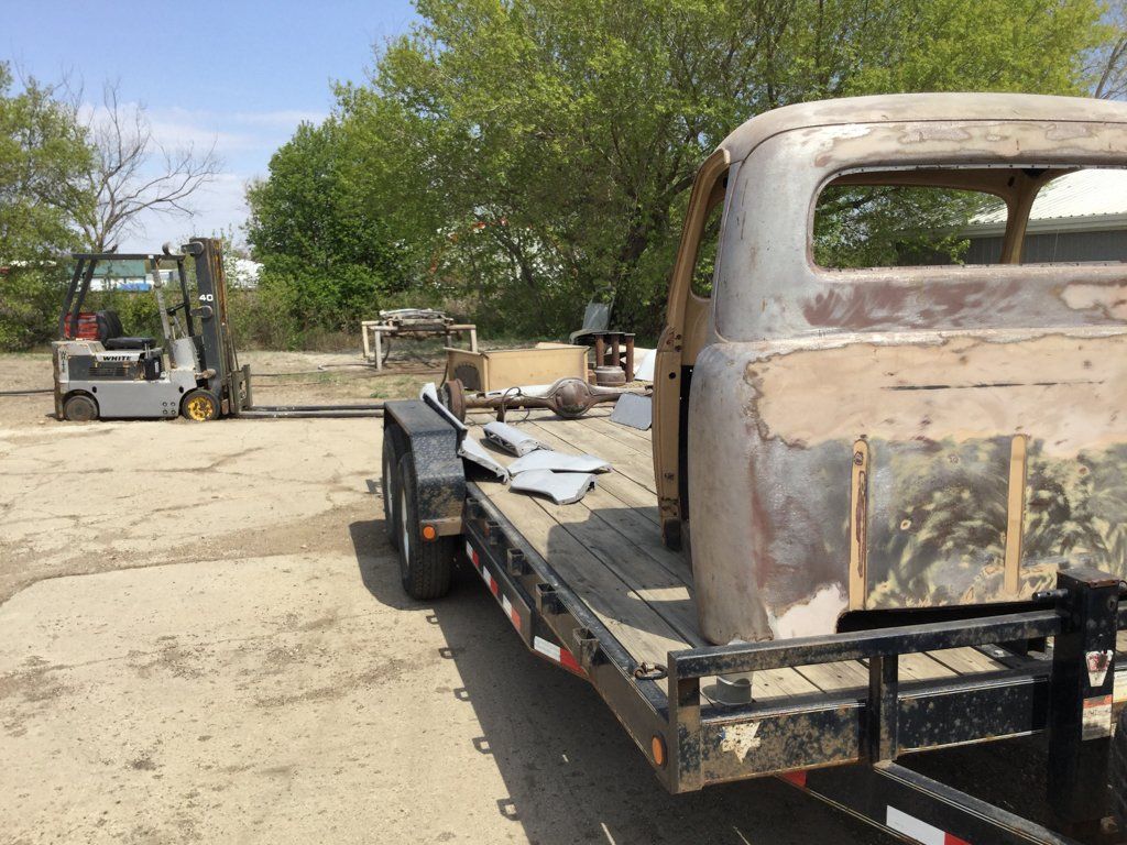 flatbed truck with truck parts on bed outdoors