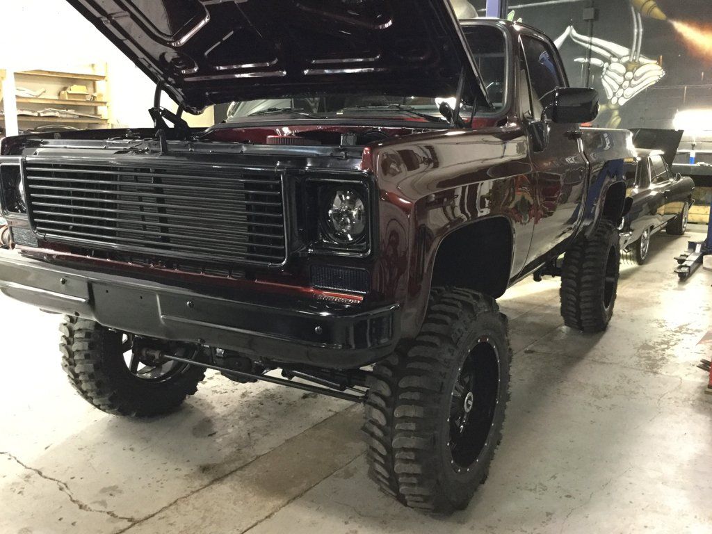 custom 1976  dark red burgundy chevy k10 pickup truck with hood open inside garage